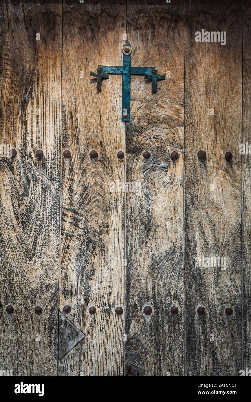 Antike Holztür mit einem gusseisernen Kreuz und eisernen Nieten Stockfoto