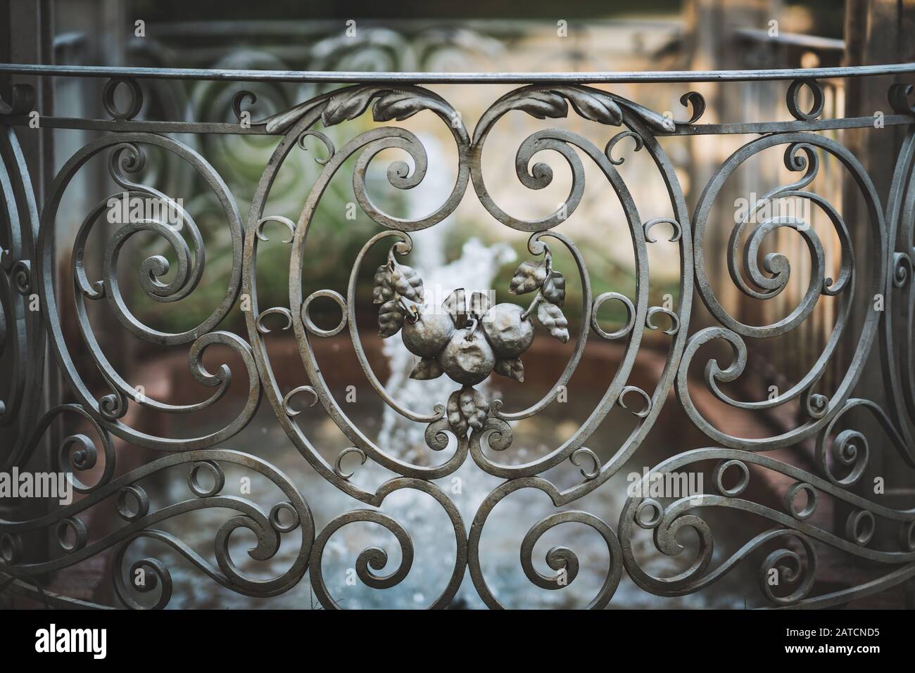 Antiker dekorativer gusseiserner Zaun im neoklassizistischen Stil, der einen kleinen romantischen Brunnen umgibt Stockfoto