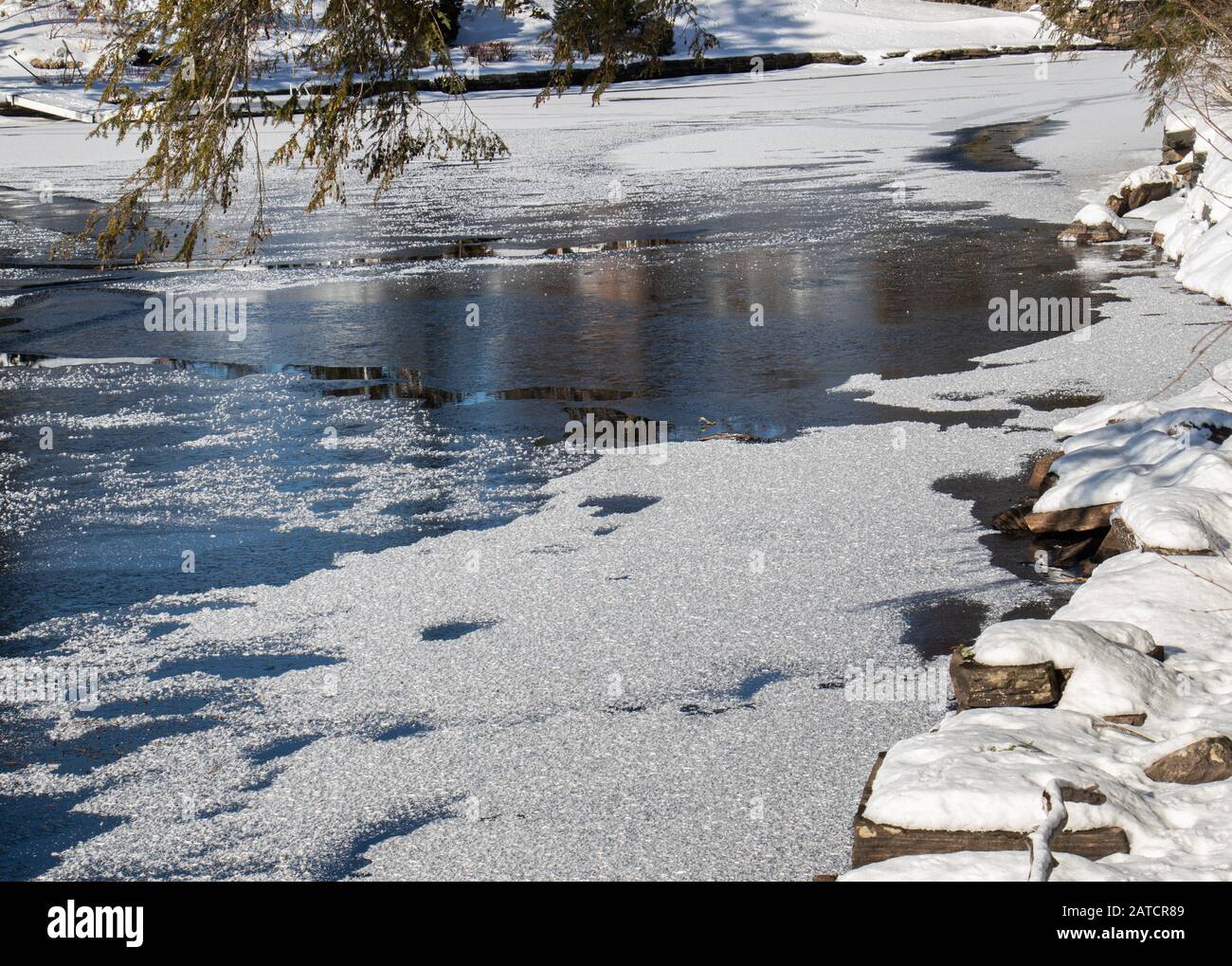 Schöner Fluss in Muskoka im Januar umgeben von Schnee und felsigen Ufern. Stockfoto