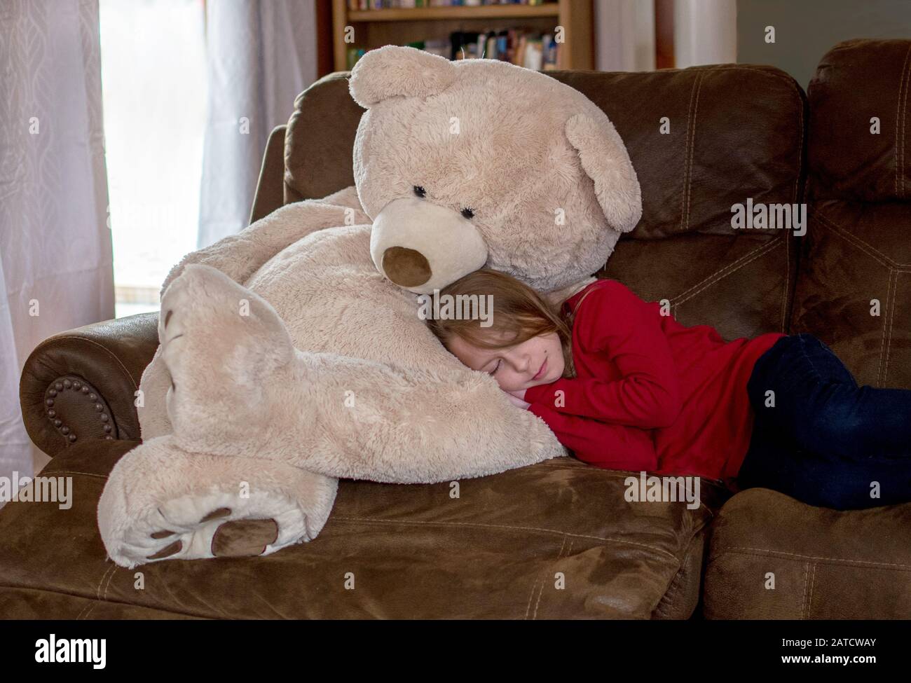 Kleine Mädchen nimmt einen Nickerchen auf den Schoß ihrer besten Bärenfreundin Stockfoto