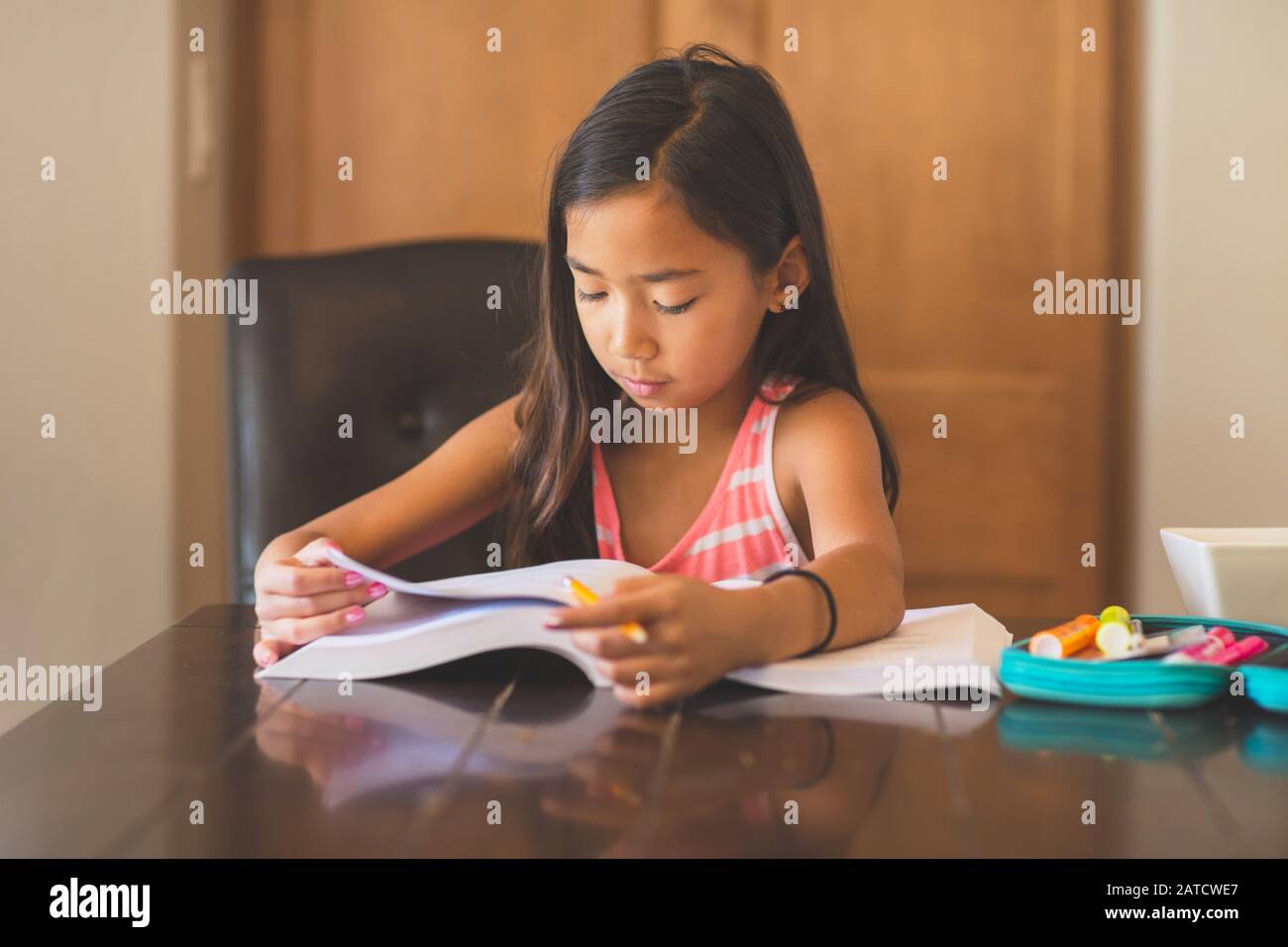 Junges Mädchen sitzt an einem Schreibtisch und arbeitet auf Ihre Hausaufgaben Stockfoto