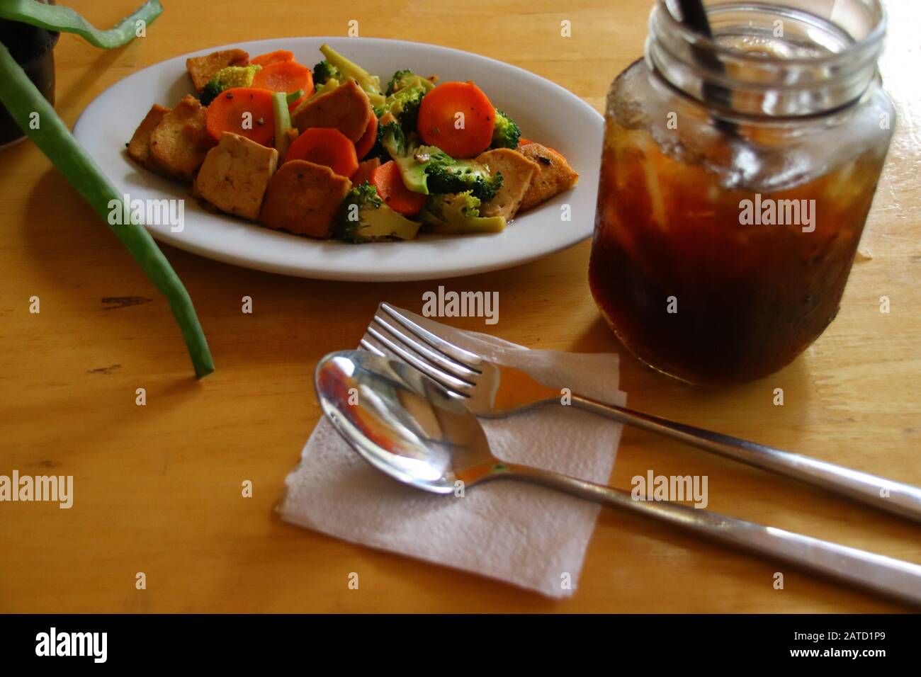 Blick von oben auf gebratenen Tofu und Gemüse und Eiskaffee, gesunde vegane Mahlzeit auf pflanzlicher Basis Stockfoto