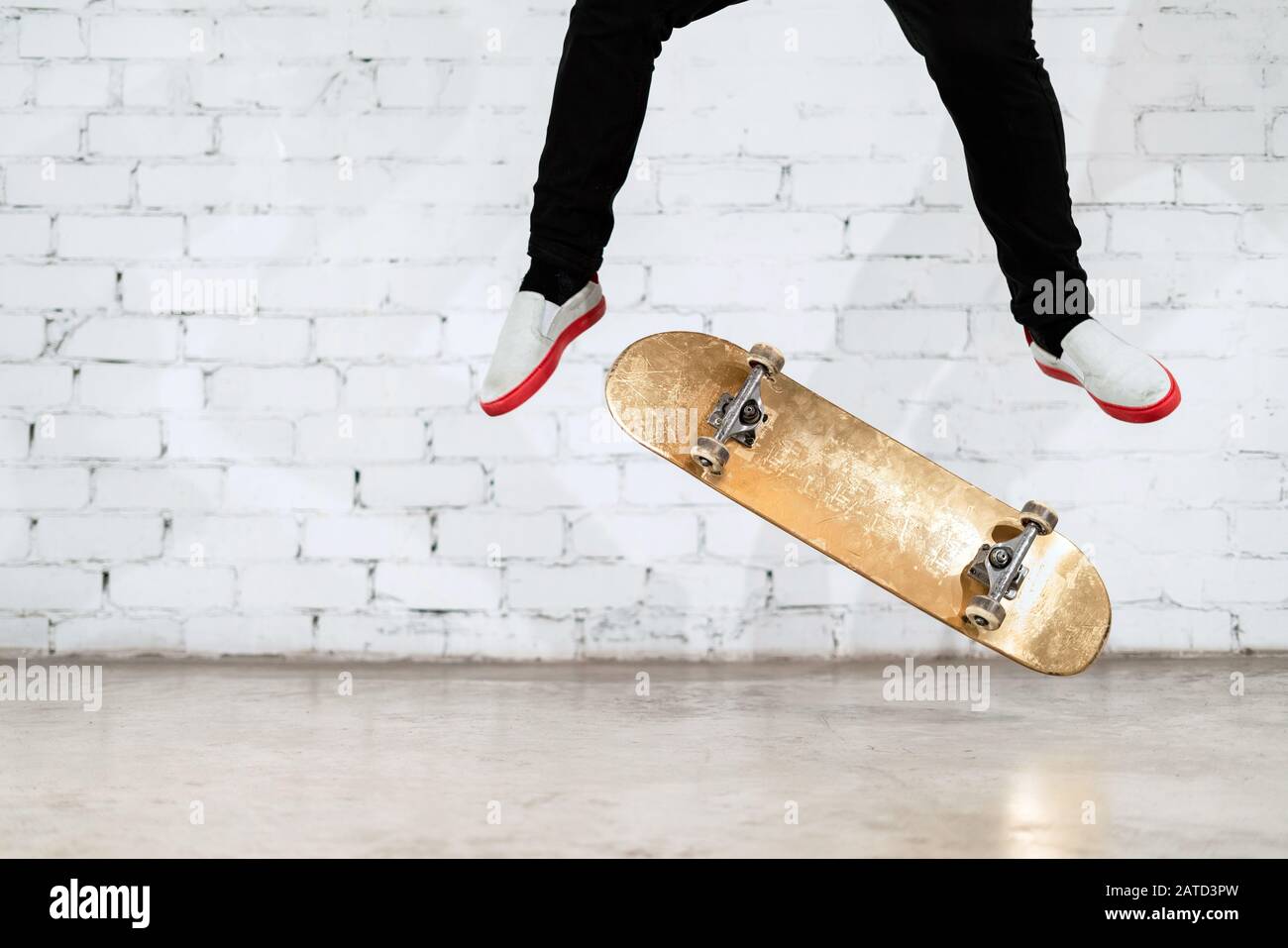 Skateboarder, der Skateboard-Trick ausführt - Kick Flip on Concrete. Olympiateilnehmer übt Sprung auf weißem Hintergrund und bereitet sich auf den Wettkampf vor. Extr Stockfoto