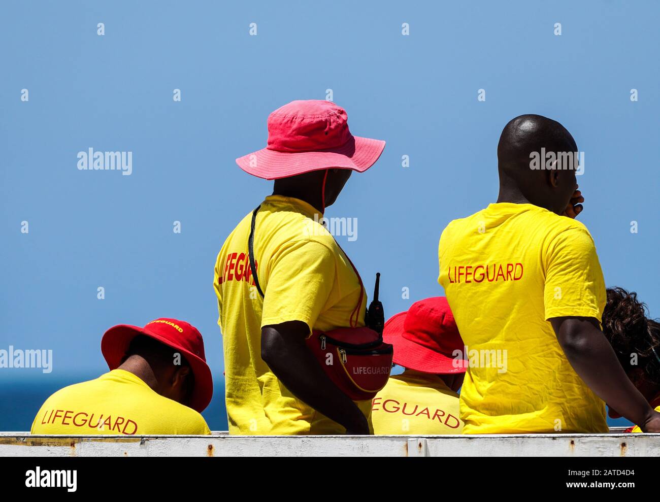 Rettungsschwimmer, Rettungsschwimmer, die in der Pflicht sind, tragen gelbe und rote Uniform an ihrem Turm am Muizenberg Strand, Kap-Halbinsel, Südafrika Konzept der öffentlichen Sicherheit Stockfoto