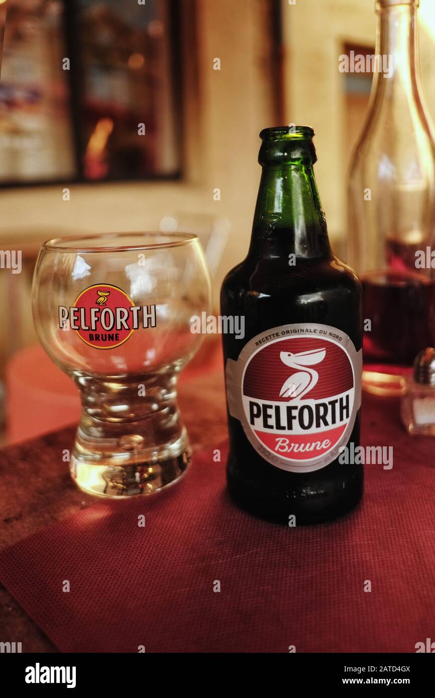Eine Flasche PELFORTH Brune dunkles Bier mit einem passenden runden  Markenglas für das nordfranzösische Bier, das am Nachmittag auf einem  Café-Tisch fotografiert wurde Stockfotografie - Alamy