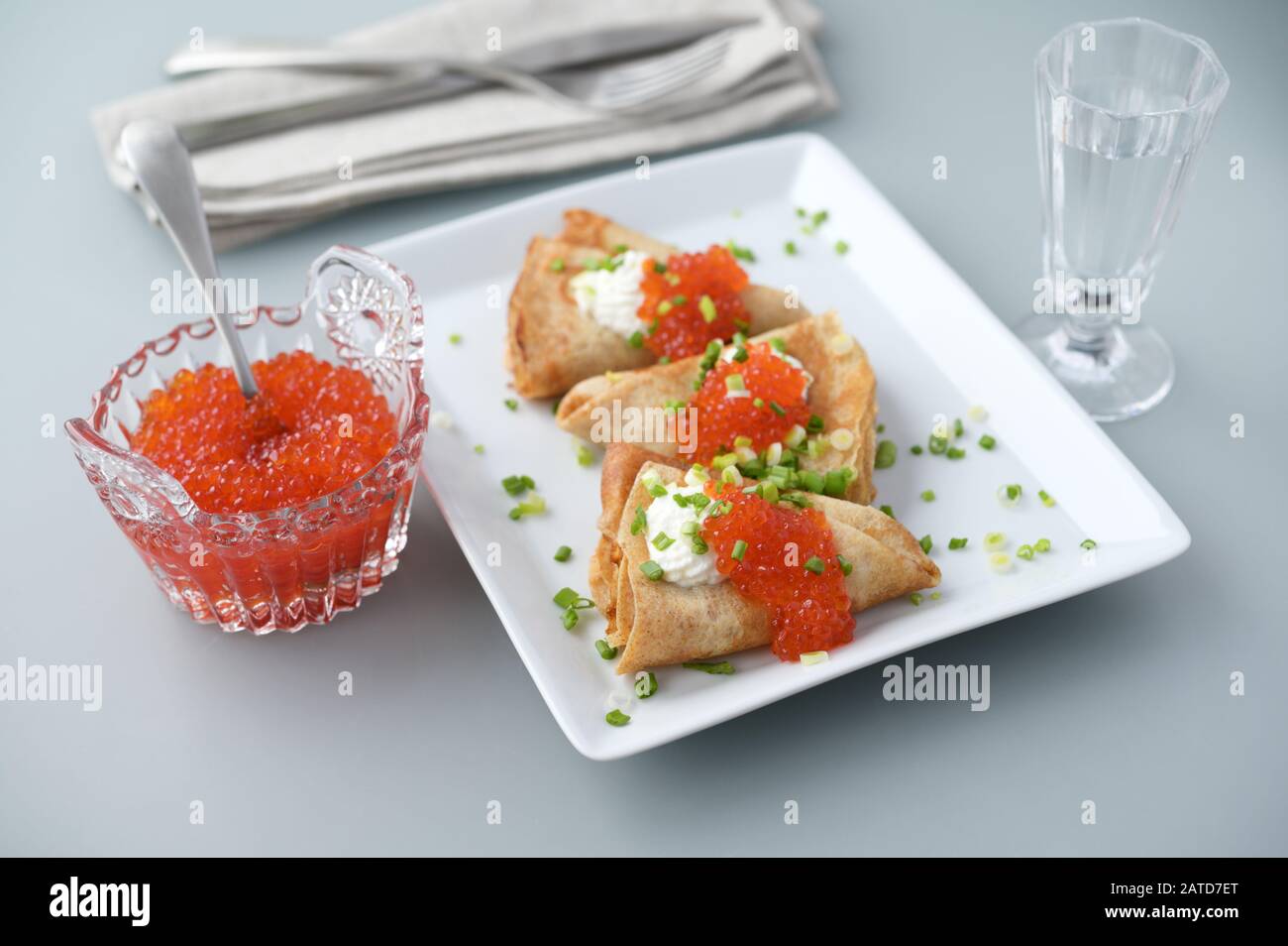 Jalois mit rotem Kaviar und saurer Sahne, die mit grüner Zwiebel verziert ist Stockfoto