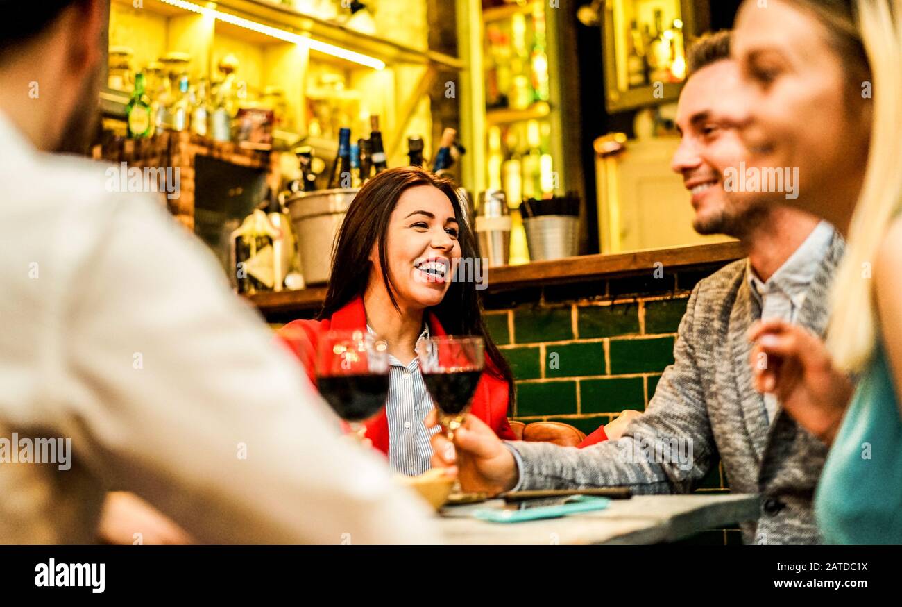Fröhliche Freunde, die in einem trendigen Cocktailbar-Restaurant lachen und Wein toben - Junge Leute, die Spaß haben, Vorspeisen zu trinken - Fokus auf linkes Gesicht der Frau - W Stockfoto
