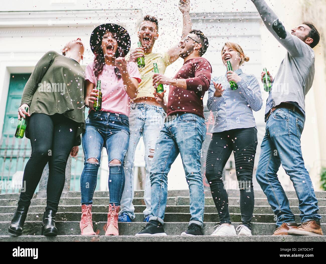 Fröhliche verrückte Freunde feiern auf der Straße Bier trinken und Konfetti werfen - Junge Studenten haben Spaß zusammen - Freundschafts- und Jugendkonzept Stockfoto