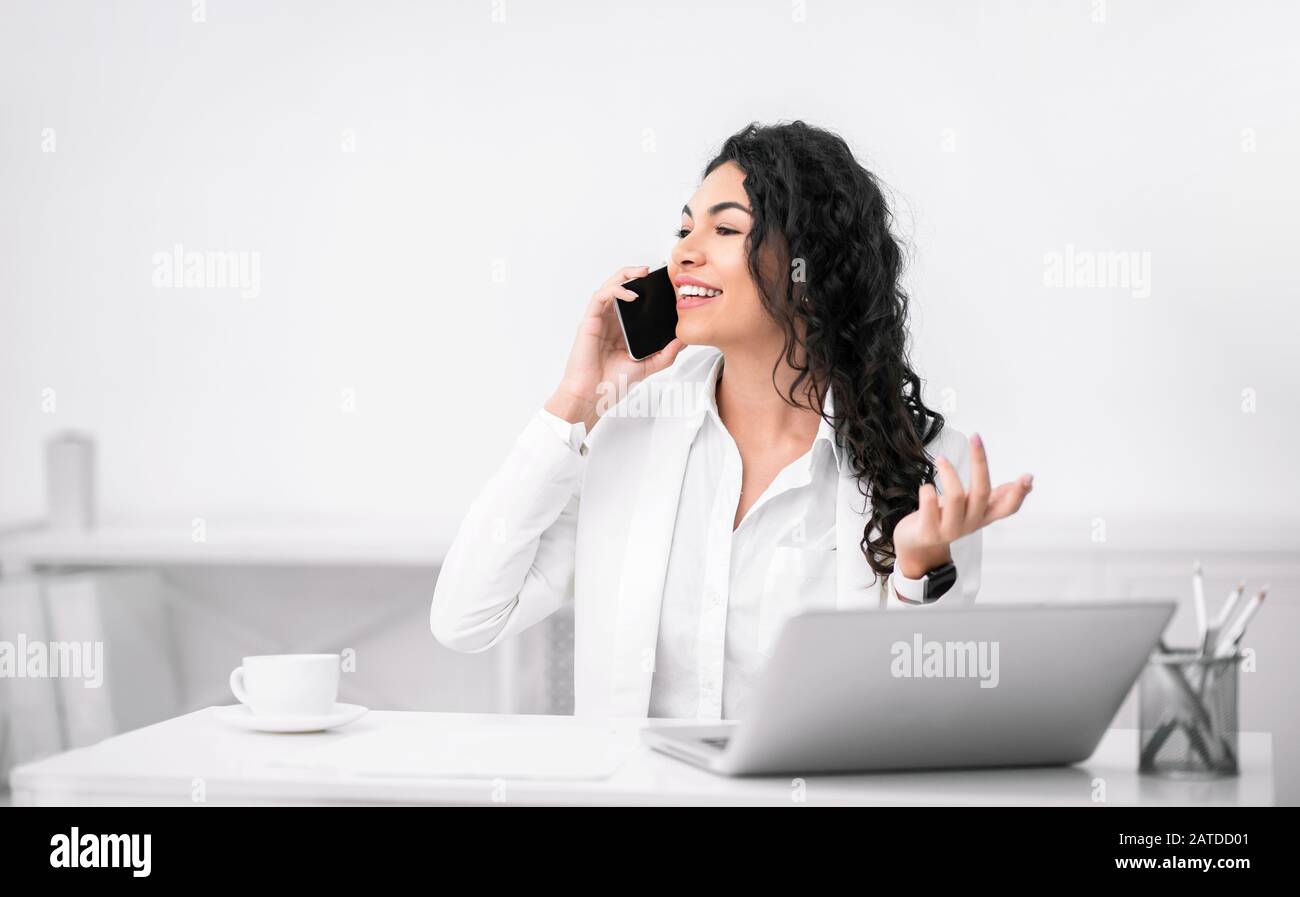 Aufgeregt hispanische Mädchen, die im Büro telefonieren Stockfoto