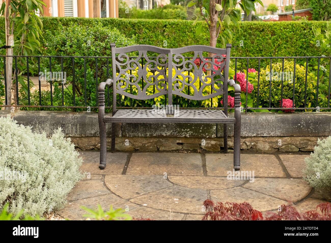 Leere schmiedeeiserne Bank mit zwei Sitzplätzen vor dem Garten des Hauses, Edinburgh, Schottland Stockfoto