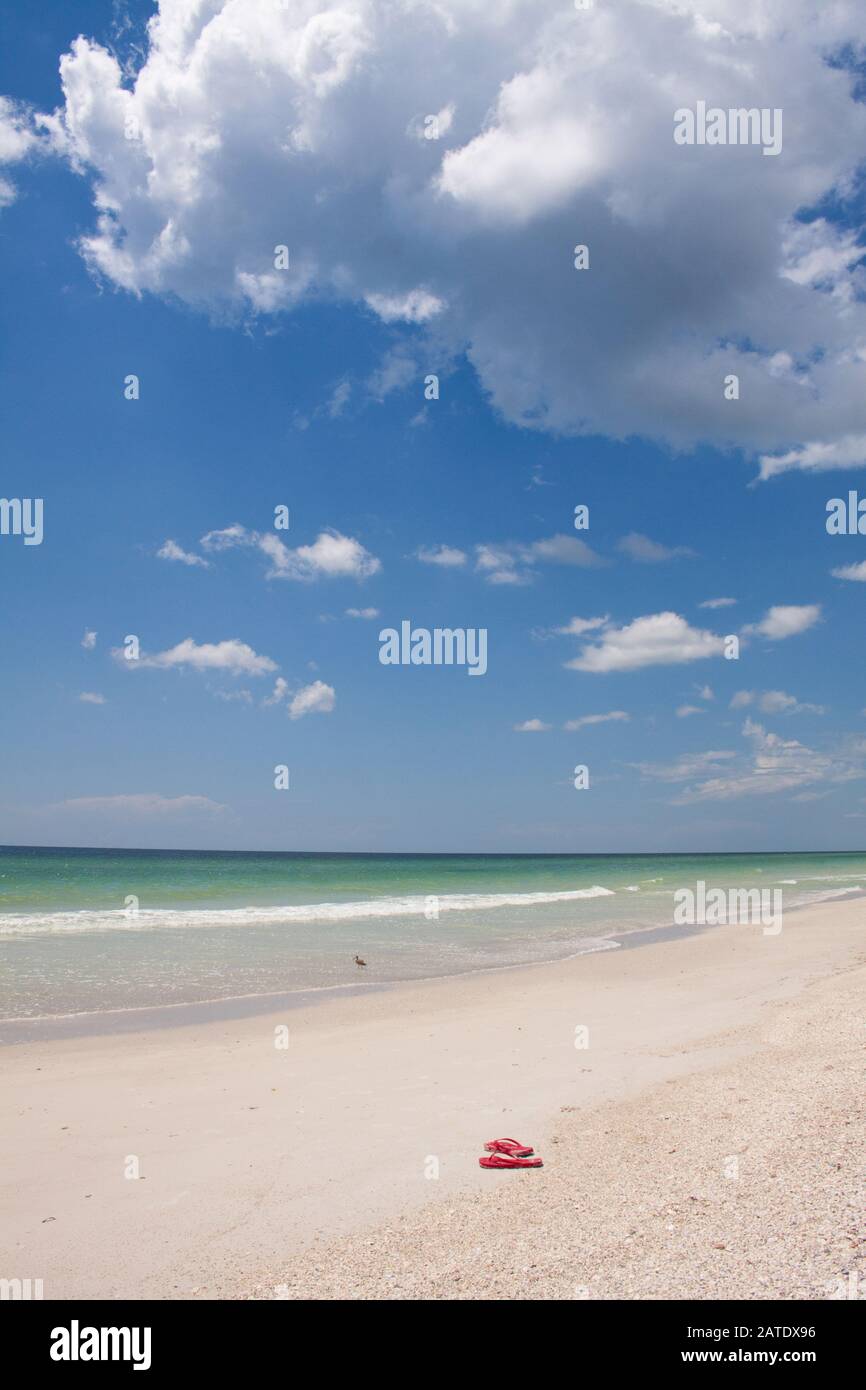 Leerer weißer Sandstrand mit nur einem Paar roten Flip-Flops in Florida, USA Stockfoto