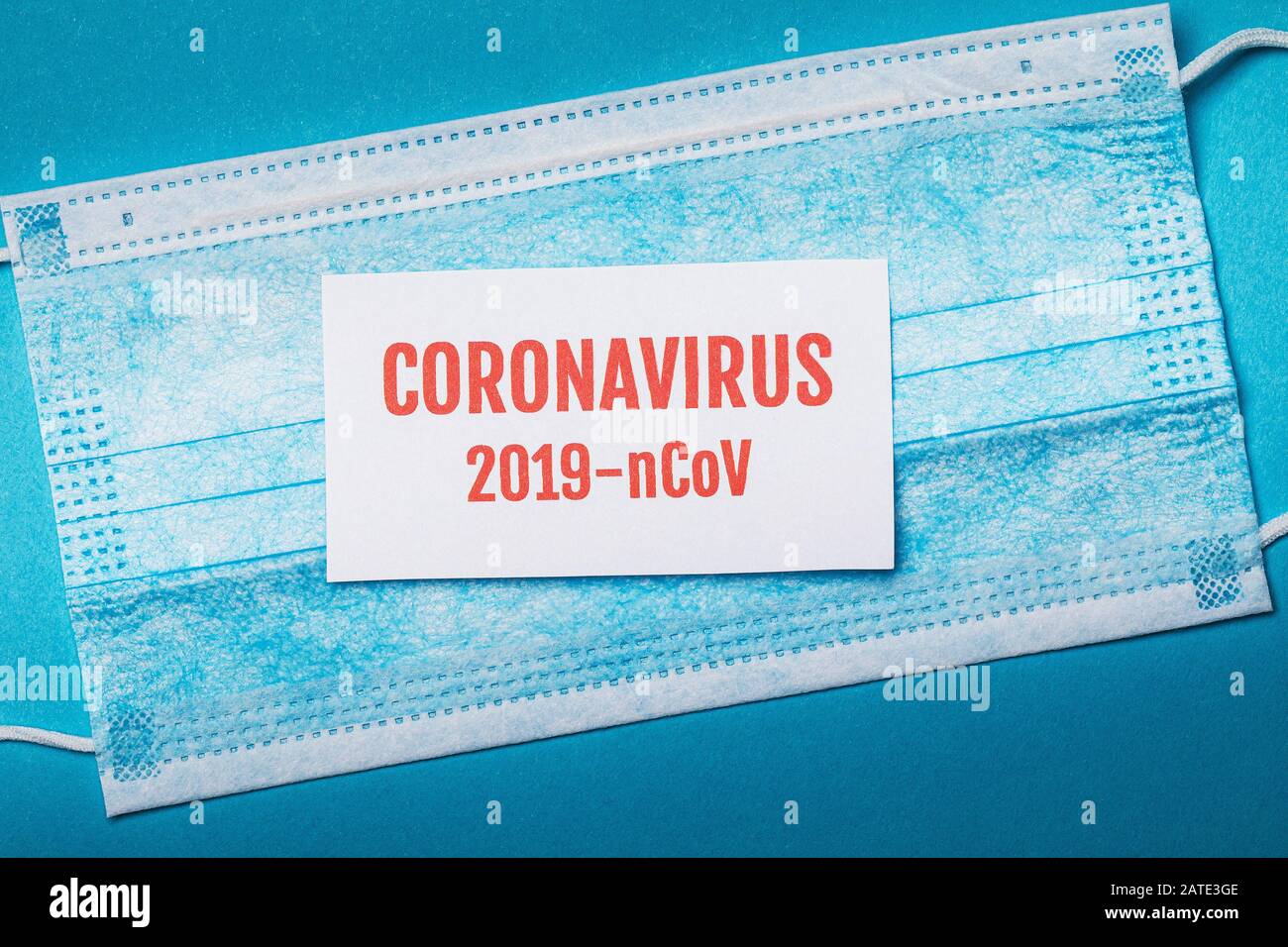 Medizinische Einwegmaske und ein Blatt Papier mit der Aufschrift, Draufsicht. Coronavirus Dangerous Pneumonia Outbreak Concept 2019-vCoV Stockfoto