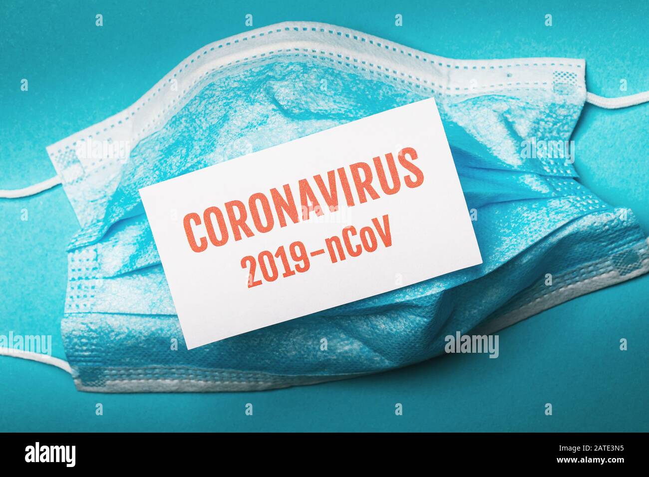 Medizinische Einwegmaske und ein Blatt Papier mit der Aufschrift Coronavirus, Draufsicht. Konzept des gefährlichen Lungenentzündung-Ausbruchs 2019-vCoV Stockfoto