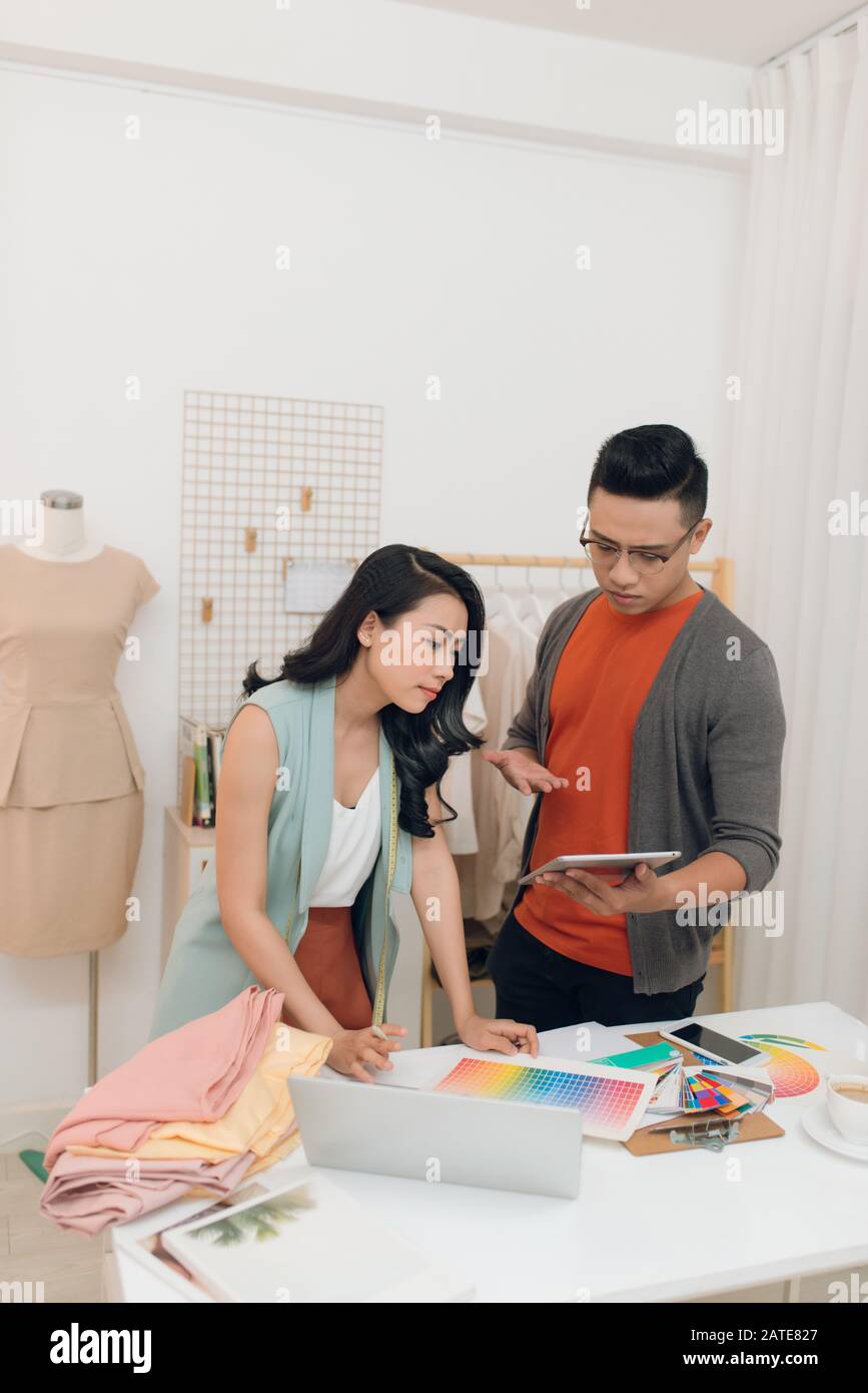 Paar Fashion Designer arbeiten in der Werkstatt, während sie Tablet/ipad zu besprechen Stockfoto