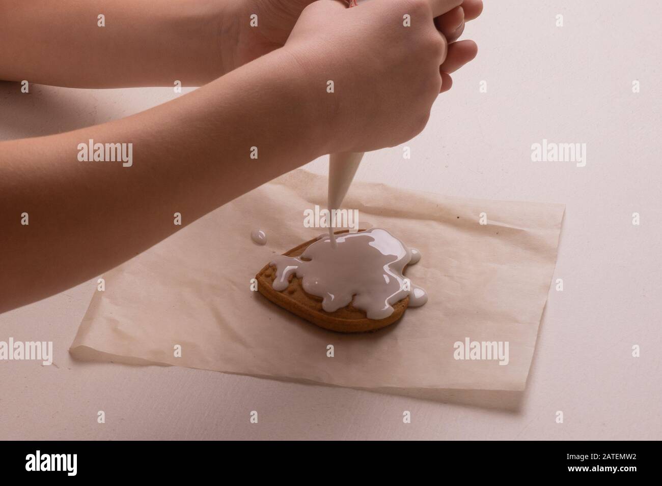Ein 10-jähriger Junge glasiert Plätzchen mit einer kulinarischen Tüte. Handgefertigt. Kreativität der Kinder Stockfoto