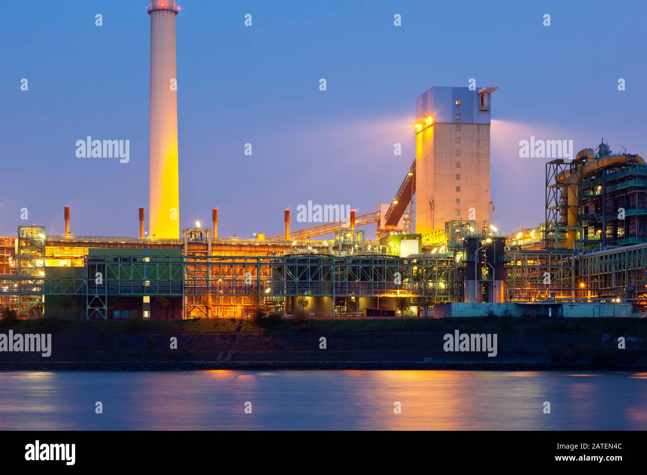 Eine Kokerei, die über einem Fluss mit blauem Nachthimmel zu sehen ist. Stockfoto