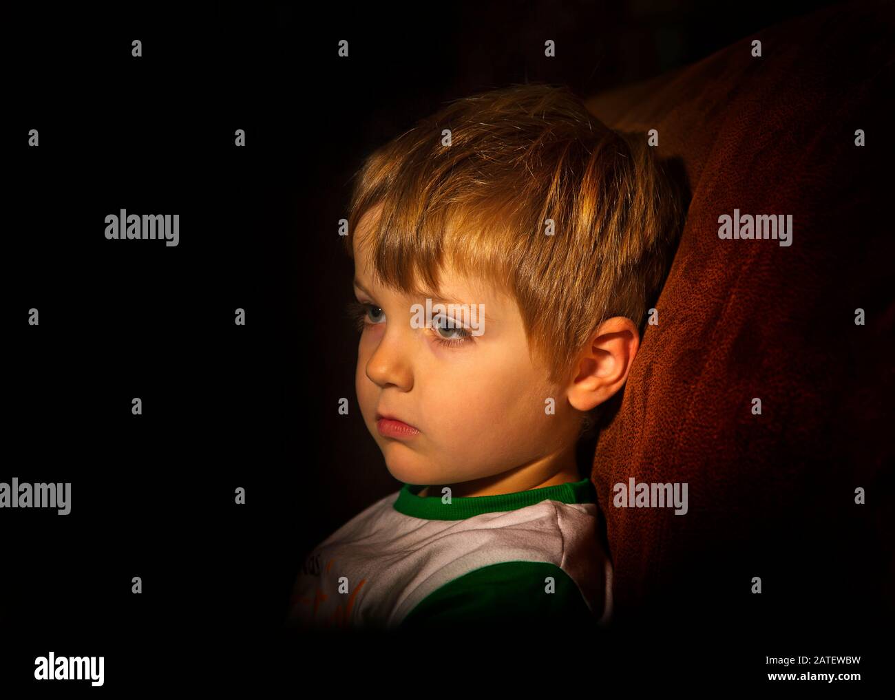 Ein kleiner Junge, der in einem Lichtschacht sitzt Stockfoto