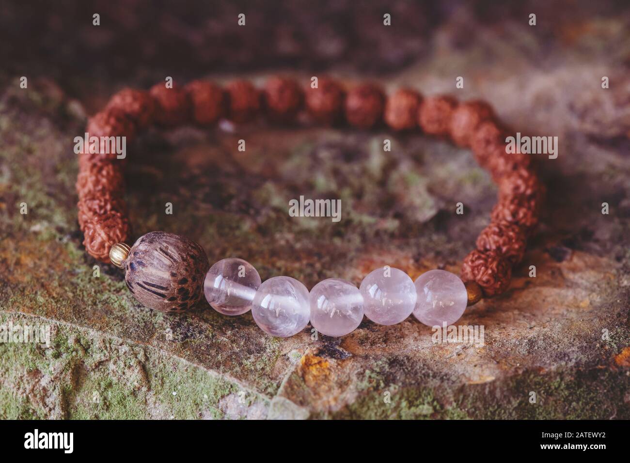 Mineralische Steinperlen und natürliche Rudraksha-Samenperlen Armband auf felsigem Hintergrund Stockfoto