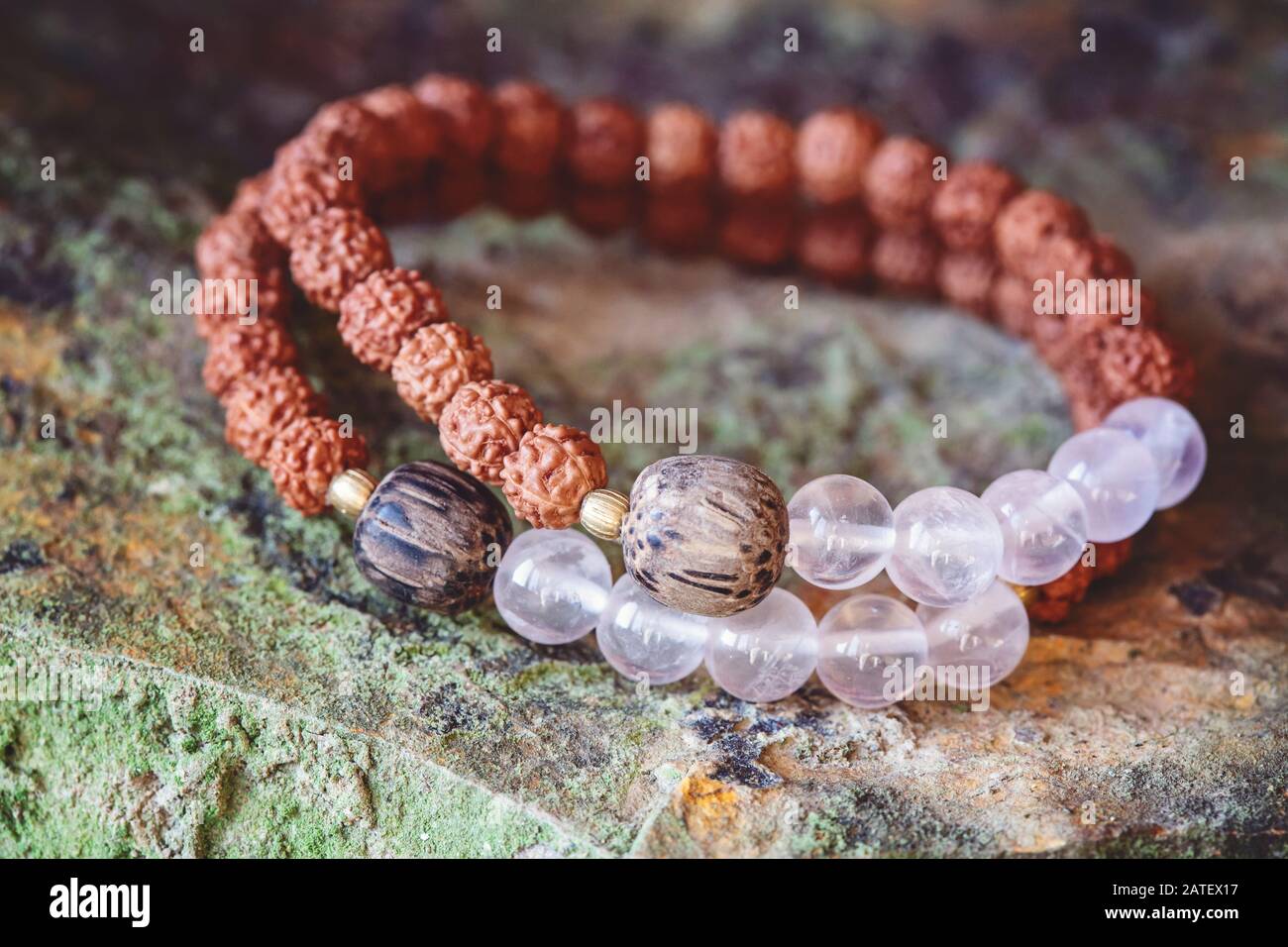 Mineralische Steinperlen und natürliche Rudraksha-Samenperlen Armband auf felsigem Hintergrund Stockfoto