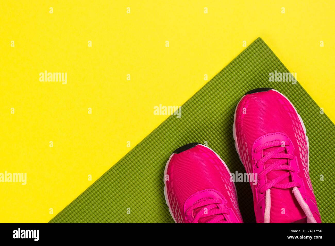 Pinkfarbene Turnschuhe und Yogamatte auf Farbhintergrund. Stockfoto