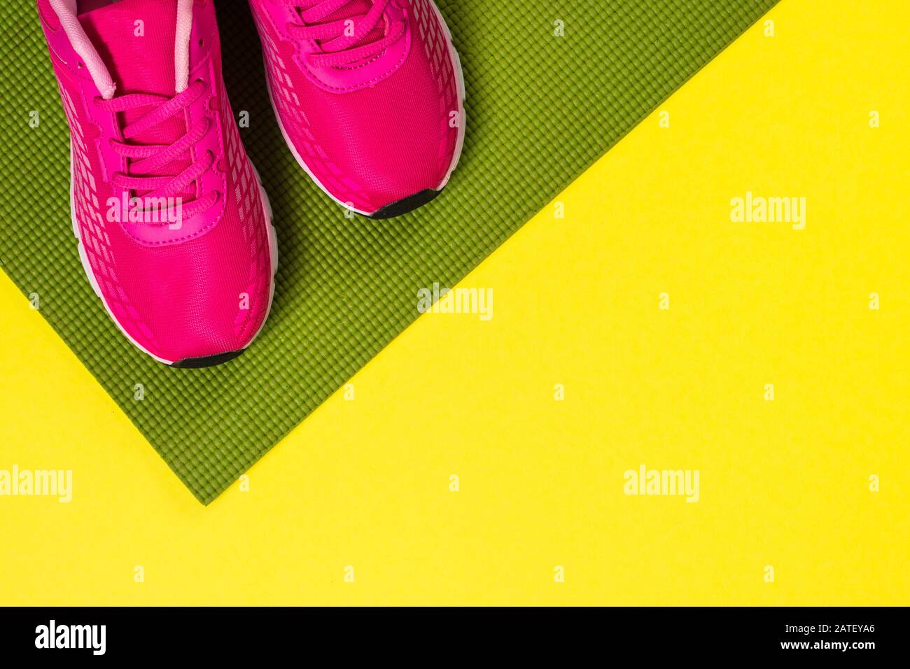 Pinkfarbene Turnschuhe und Yogamatte auf Farbhintergrund. Stockfoto