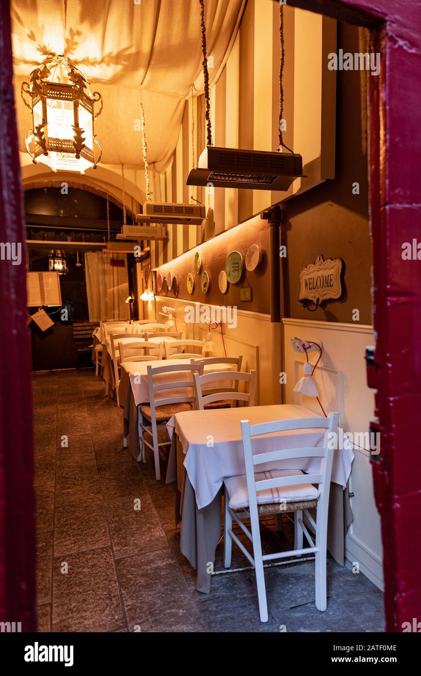 Eingang zu einem historischen Restaurant mit weißen Tischen und Stühlen und einem großen Kronleuchter, der ein warmes Licht diffus macht Stockfoto
