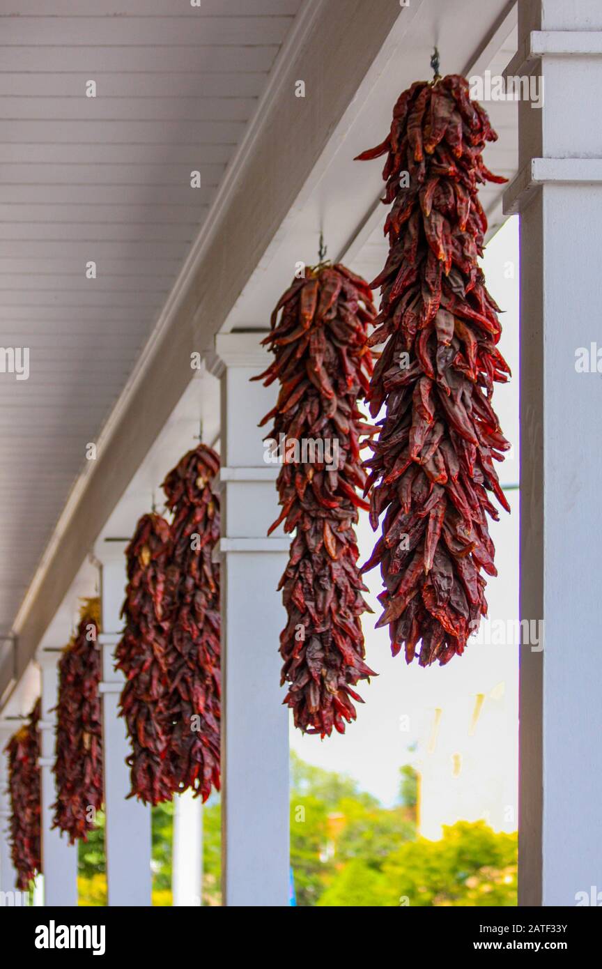 Rote chilischoten hängen im Außenbereich des Gebäudes in New Mexico, USA als Dekoration. Santa Fe, Vereinigte Staaten von Amerika. Schnur aus getrocknetem Pfeffer Stockfoto