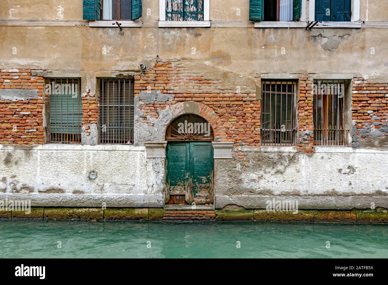 Eine alte grüne Tür in einem alten Lagergebäude führt zurück auf den kanal rio de San Marcuola Im Bezirk Cannaregio, Venedig, Italien Stockfoto