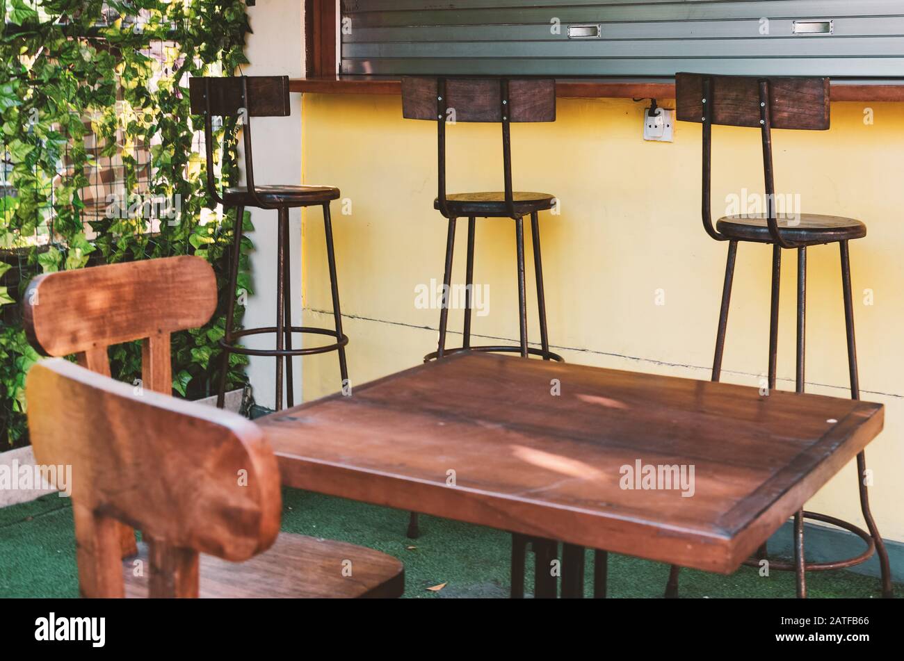 Blick auf den Innenhof eines Cafés im Freien an einem sonnigen Tag. Holzmöbel - Barhocker und Tische. Bali, Indonesien Stockfoto
