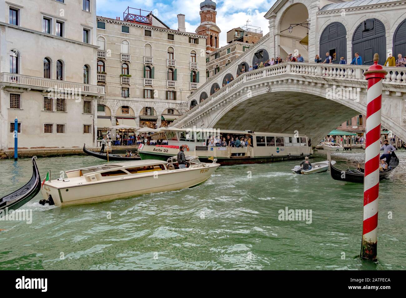 Wassertaxi, Vaporetto und andere kleine Boote machen sich unter Der Rialtobrücke auf den Weg, die älteste von vier Brücken, die den Canal Grande in Venedig überqueren Stockfoto