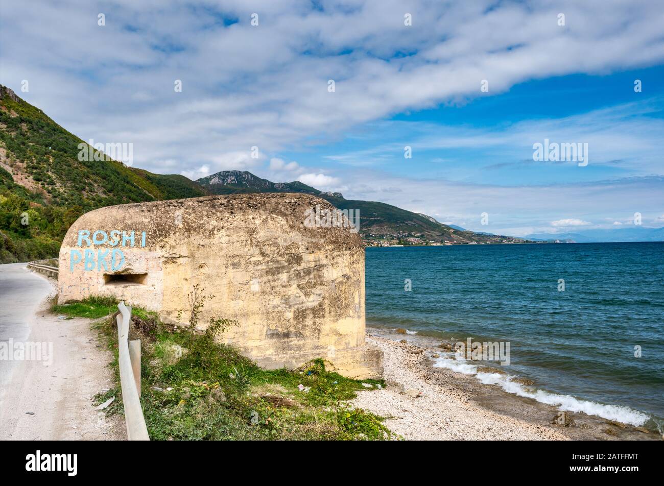 Unter dem kommunistischen Diktator Hoxha errichteter, mit Graffiti bedeckter Bunker am Ohridsee, mazedonisches Ufer in der Ferne, in der Nähe von Pogradec, Albanien Stockfoto