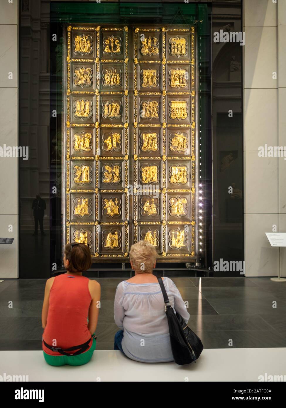 Zwei Touristen bewundern die ursprünglichen Nordtüren von Lorenzo Ghiberti aus dem Dom von Florenz im Museum der Kathedrale Stockfoto