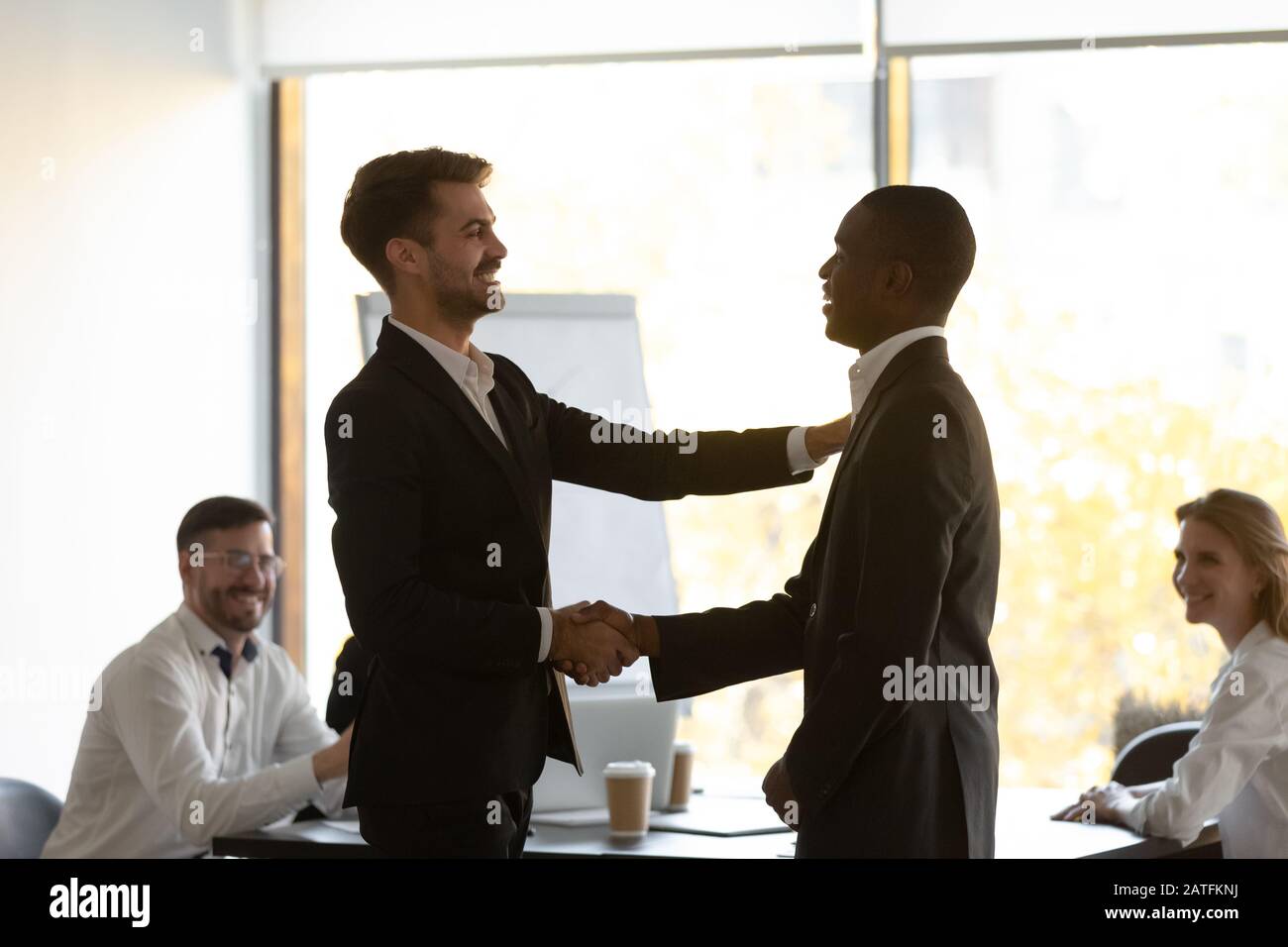 Chef lobt Handshaking afrikanischer Mitglieder während der Briefing im Sitzungssaal des Büros Stockfoto