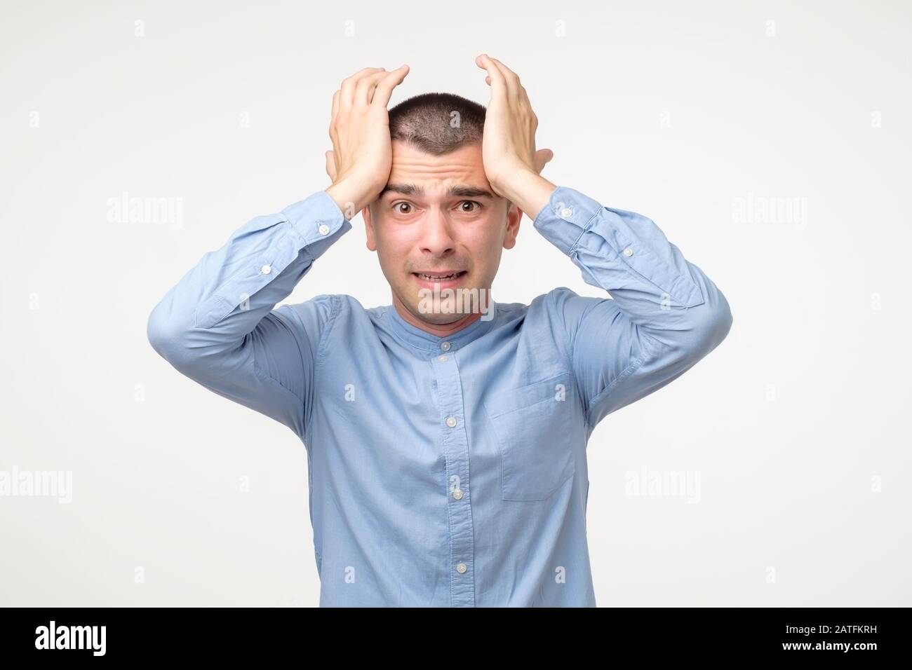 Stressiger junger hispanischer Mann in blauem Hemd. Destruktives Verhalten. Studio gedreht Stockfoto