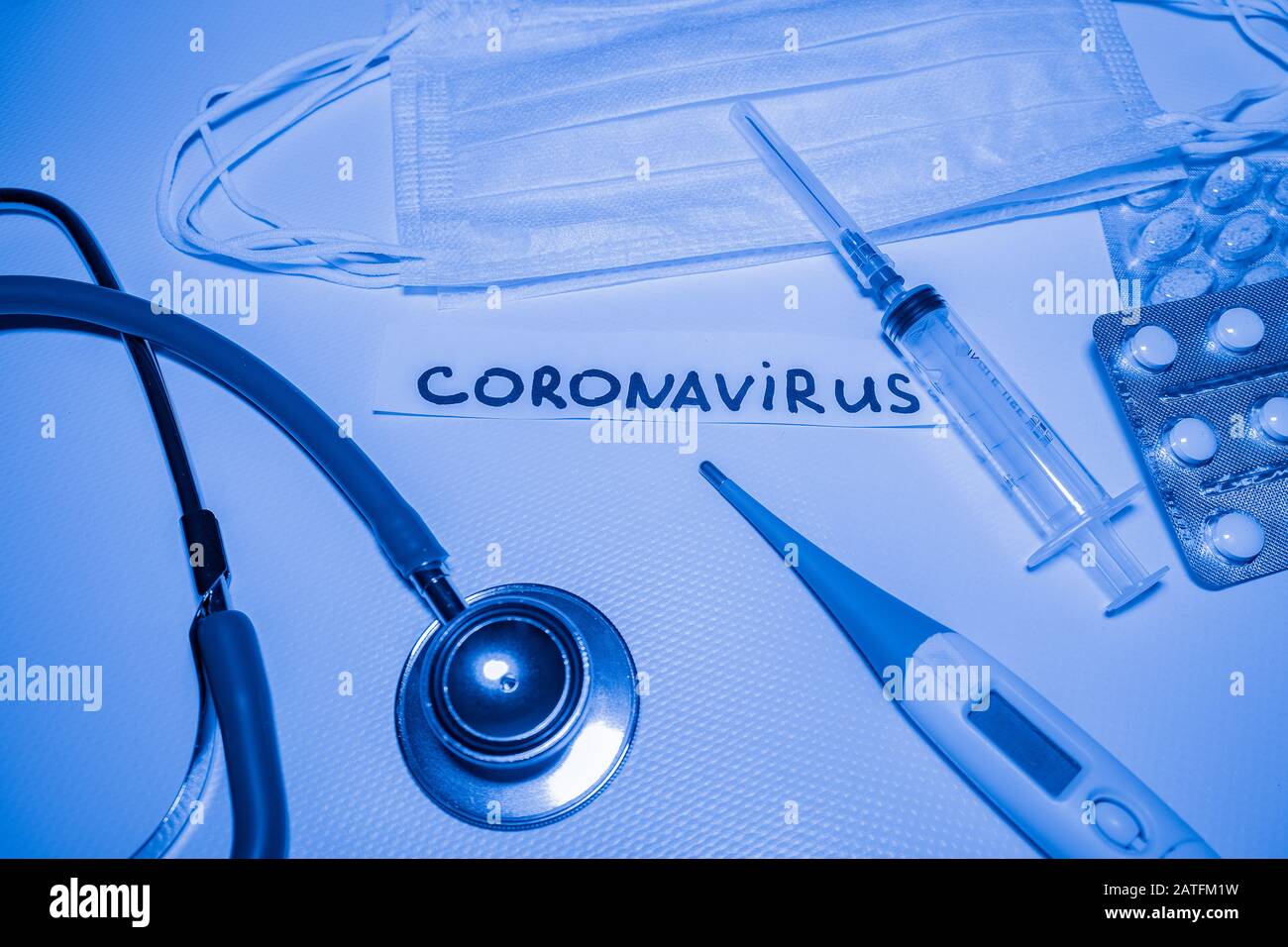 Medizinischer blauer Hintergrund mit Aufschrift Coronavirus, Stethoskop, Pillen, Thermometer, Spritze Stockfoto