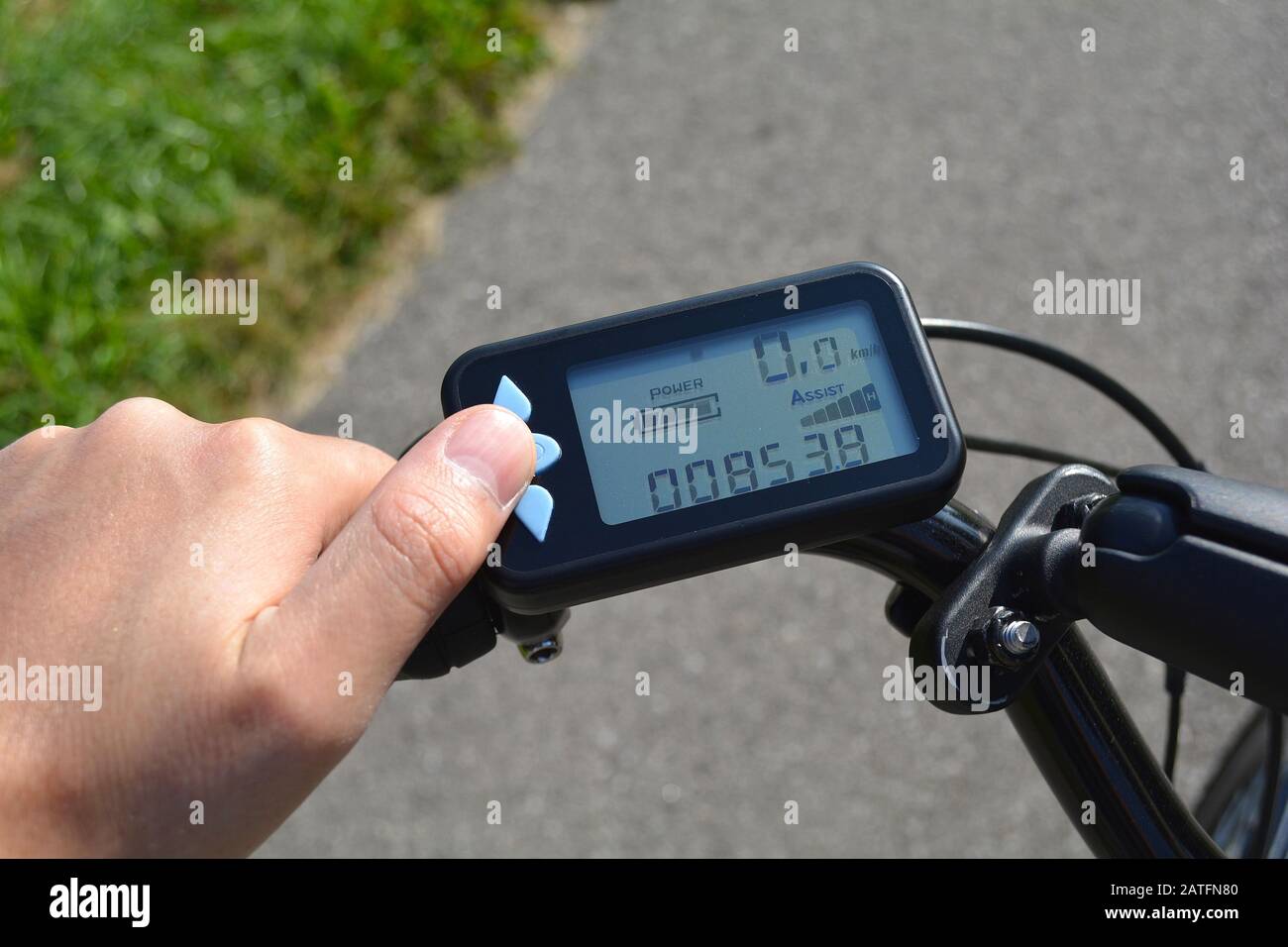 Eine männliche Hand drückt eine Taste auf einem schwarzen elektronischen Fahrrad Roller. Fahrrad Computer auf ein Fahrrad Lenker installiert. Mann sie auf eine Taste e-bike Stockfoto