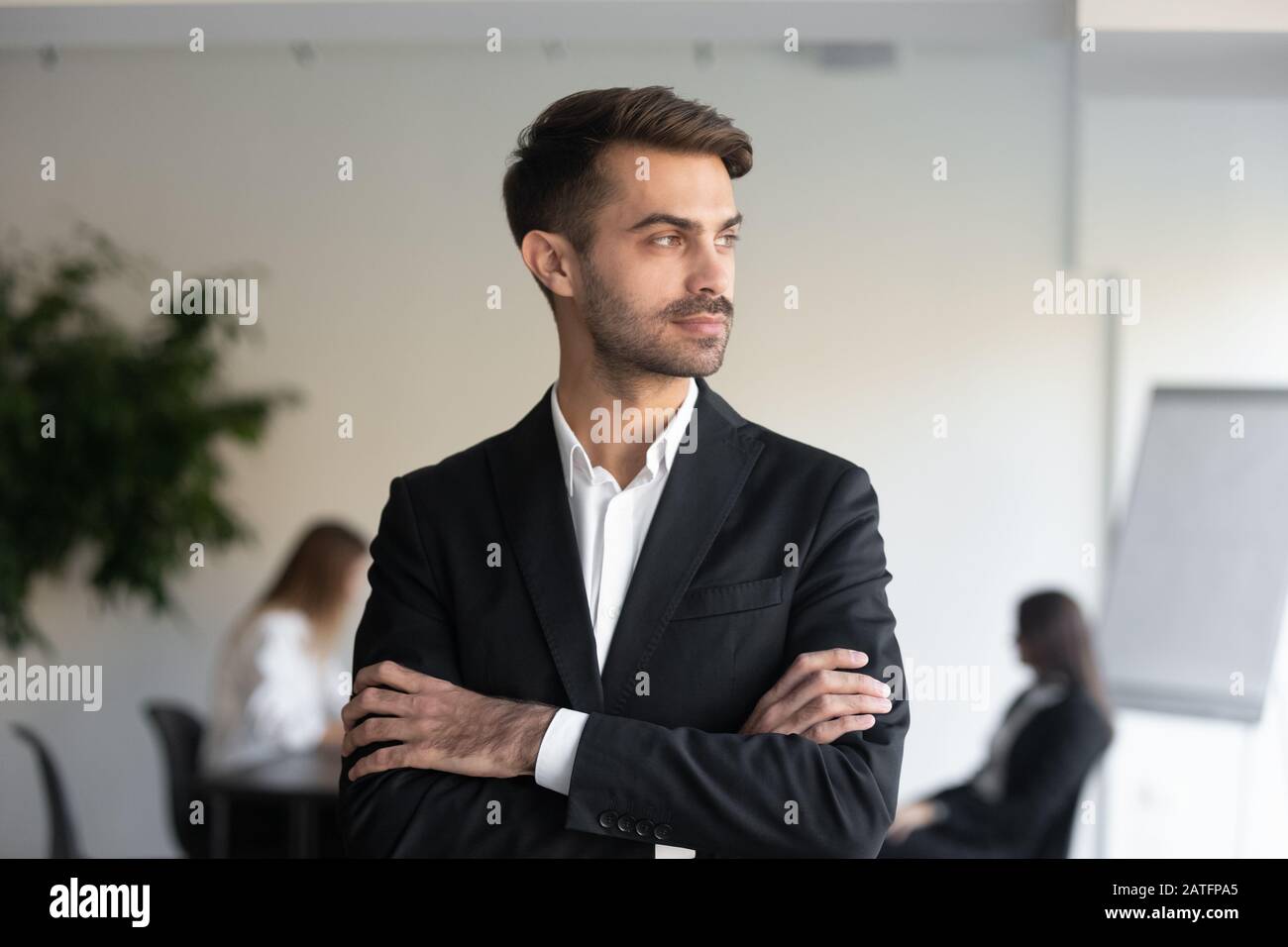 Selbstbewusster, tausendjähriger Geschäftsmann im formellen Anzug, der sich im Innenbereich aufstellt Stockfoto