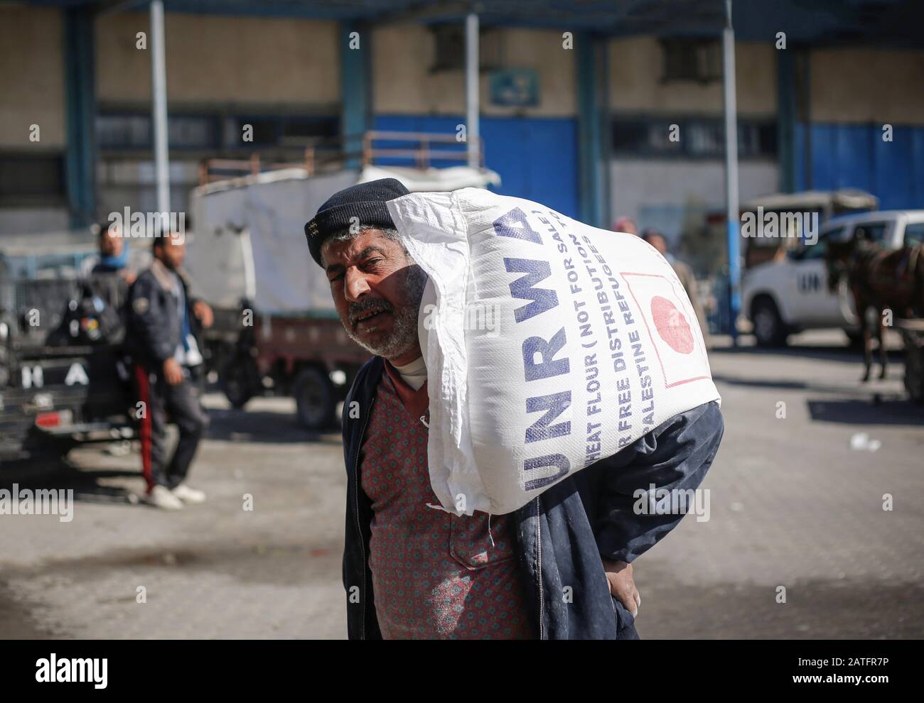 Ein Mann trägt einen Sack Mehl Teil der Nahrungsmittelhilfe des Hilfswerks der Vereinten Nationen (UNRWA) in einem Verteilzentrum im Khan Yunis Lager für palästinensische Flüchtlinge im südlichen Gazastreifen. Stockfoto