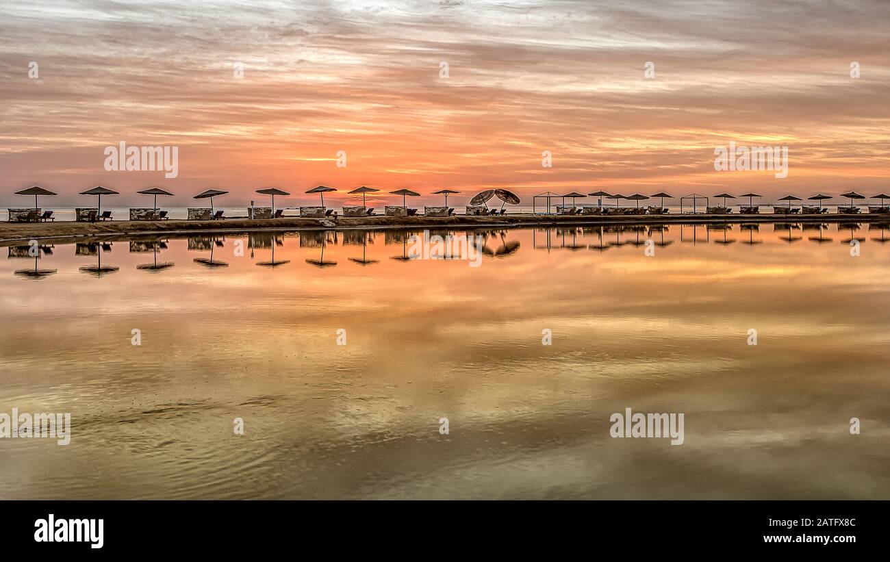 Sonnenliegen und Sonnenschirme stehen an einer Bank im roten Meer in einer langen Reihe bei Sonnenuntergang, El Gouna, Ägypten, Jnuary 16, 2020 Stockfoto