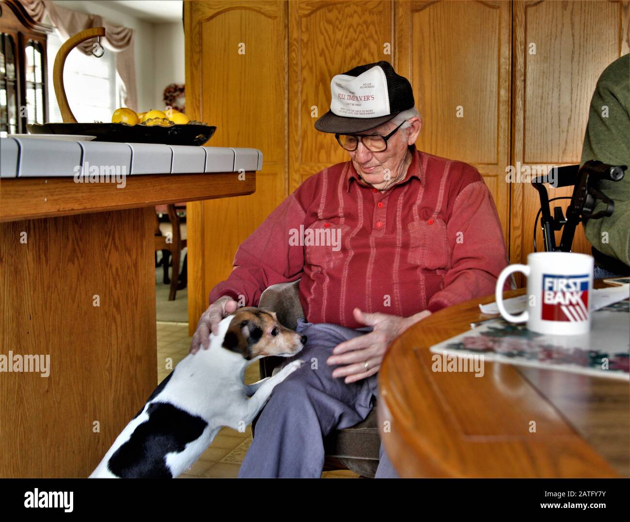 Ein hochrangiger kaukasischer Mann mit Brille und Hut mit seinem treuen Hund Jack Russel zu Hause während der Morgenkaffezeit Stockfoto