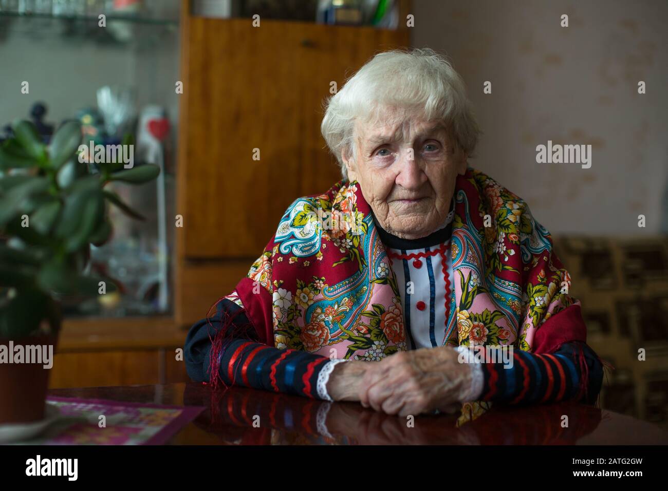 Eine alte Frau in ukrainischer Kleidung, die zu Hause sitzt. Stockfoto