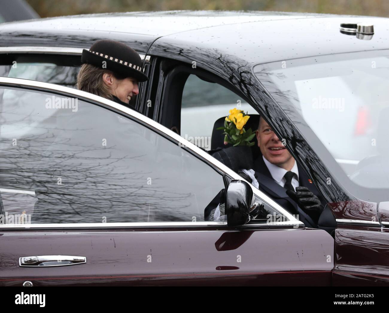 Sandringham, Großbritannien. Februar 2020. Der Fahrer des Autos der Königin erhält Blumen von einer Person in der Menge, bereit für den Valentinstag. Königin Elizabeth II. Besucht den Sonntagmorgen in der St. Peter & St. Paul Church in West Newton, in der Nähe von Sandringham, Norfolk. Ihre Majestät macht auch den kurzen Spaziergang zum Dorfhaus und trifft viele Wohlhabende, die die Strecke säumen. West Newton, Norfolk, am 2. Februar 2020. Credit: Paul Marriott/Alamy Live News Stockfoto