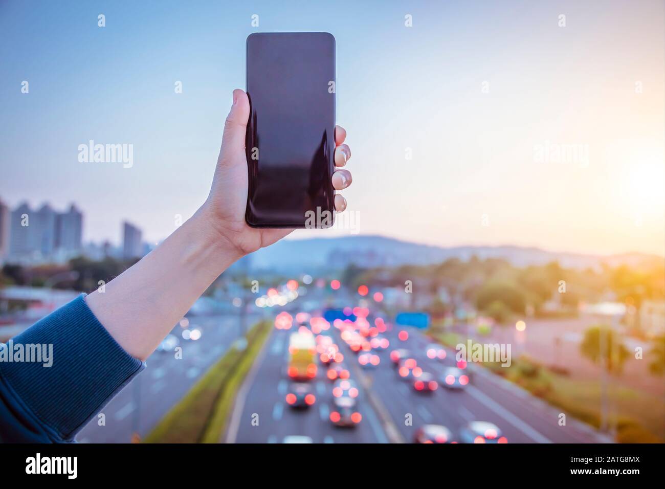 Halten Sie das Smartphone mit dem Hintergrund der Konzepte des Stadtverkehrs in der Hand Stockfoto