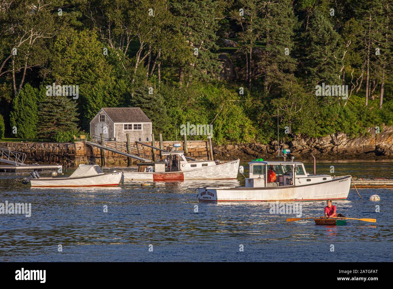 Mann, der zu seinem Boot in Rockport Harbor, Maine rudert Stockfoto