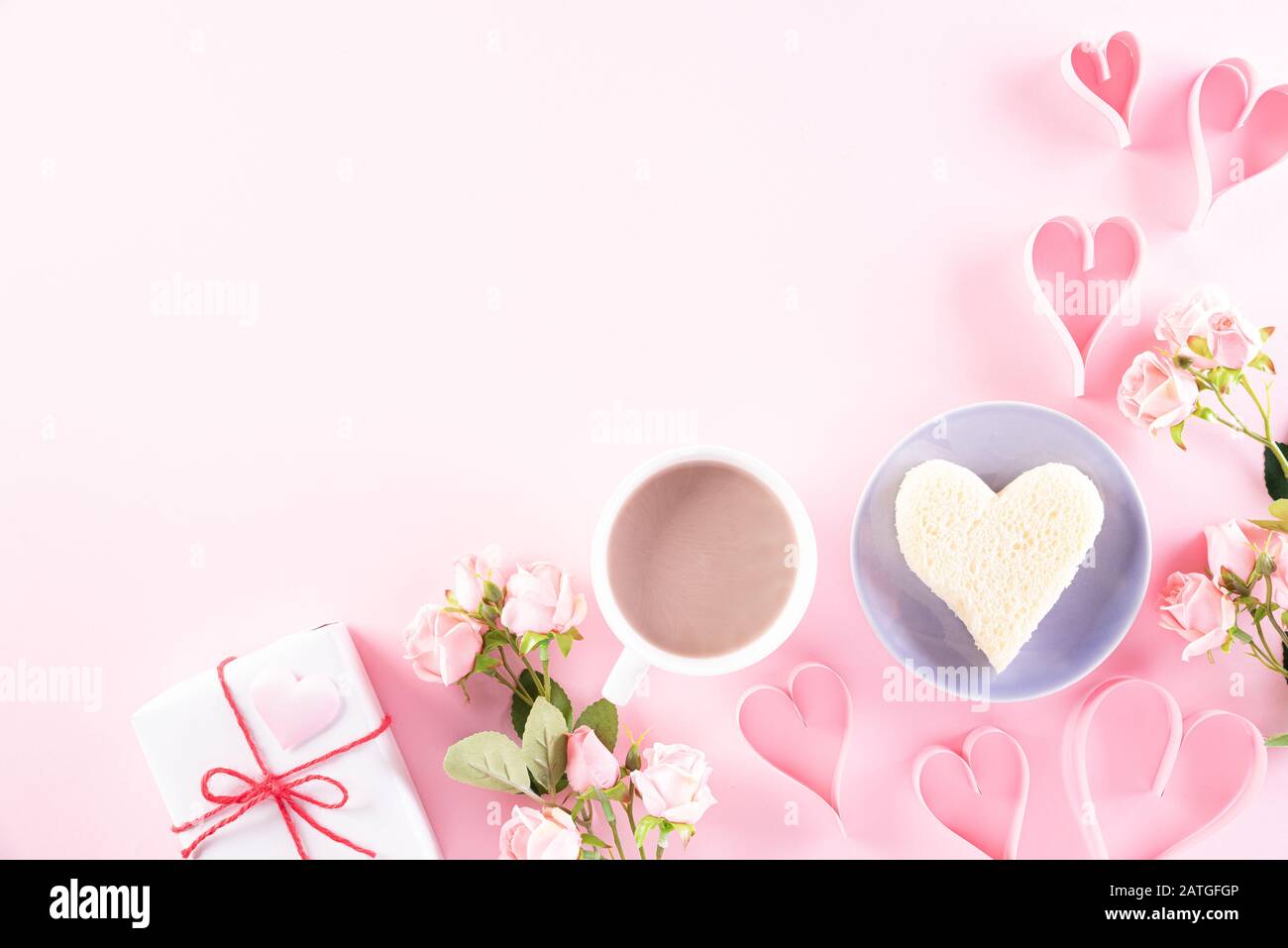 Rosa Papierherzen mit Geschenkbox, Kaffee und Rosen auf Hellrosa Pastellpapier Hintergrund. Liebe und Valentinstag Konzept. Stockfoto