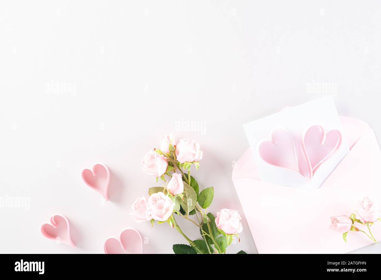 Rosa Papierherzen mit Geschenkbox und Rosen auf Hellrosa Pastellpapier Hintergrund. Liebe und Valentinstag Konzept. Stockfoto