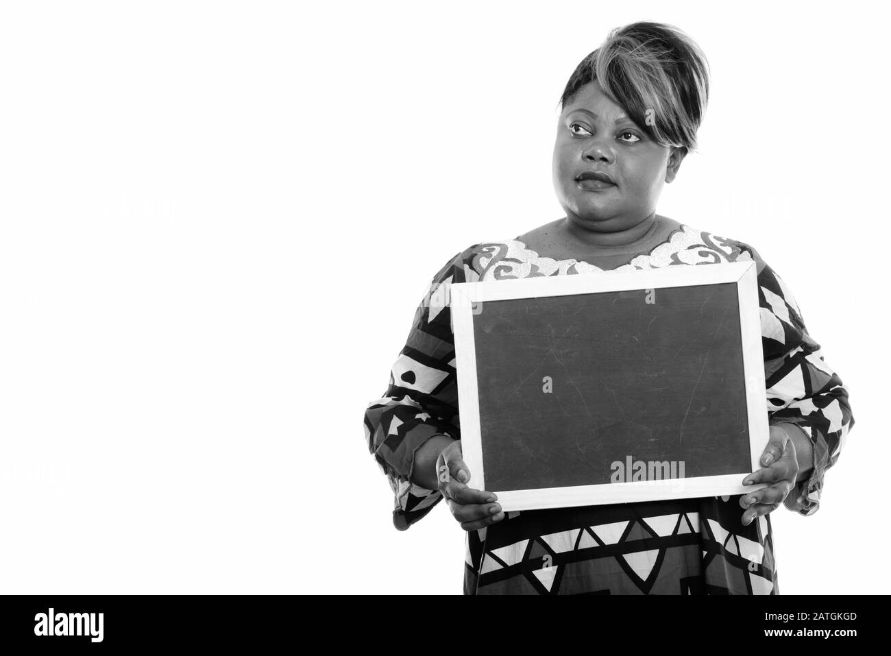 Porträt einer schönen übergewichtigen Afrikanerin, die denkt, während sie an der Tafel festgehalten wird Stockfoto