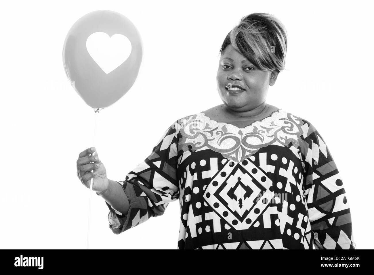 Glückliche übergewichtige Afrikanerin hält Ballon mit Herzschild bereit für Valentinstag Stockfoto