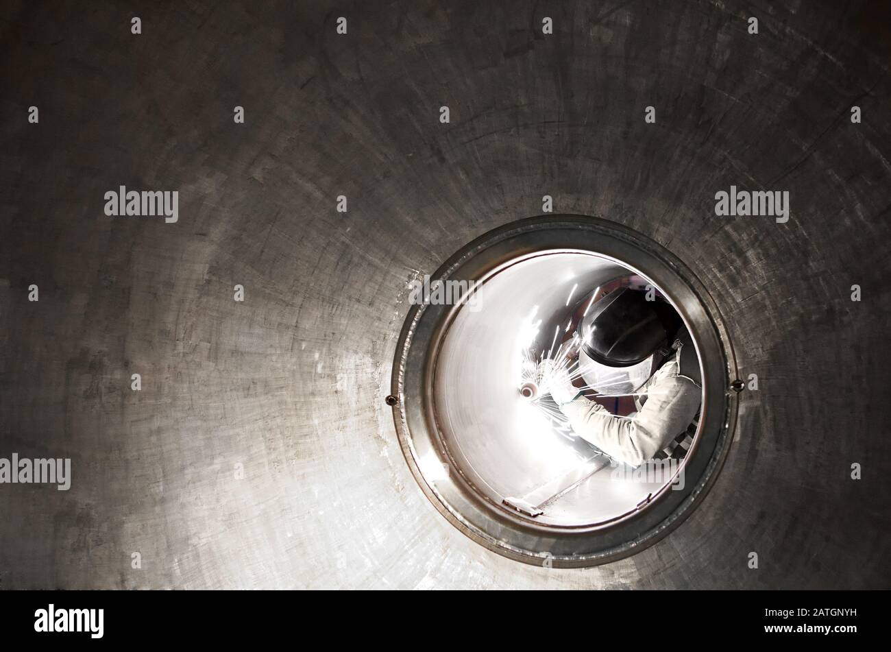Schweißer oder Metallarbeiter, die in einem Tunnel arbeiten, sahen die Länge nach unten, wobei die Perspektive zurückging, die ihn während seiner Arbeit umrahmt Stockfoto