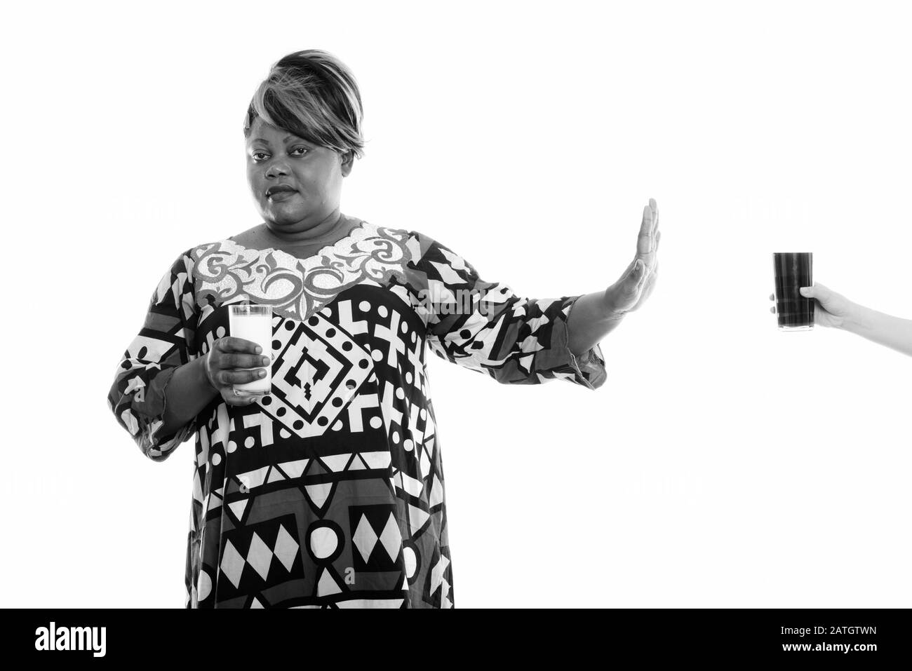 Studio-Schuss von fettschwarzer Afrikanerin, die Glas Milch hält, während sie Glas Limonade ablehnt Stockfoto